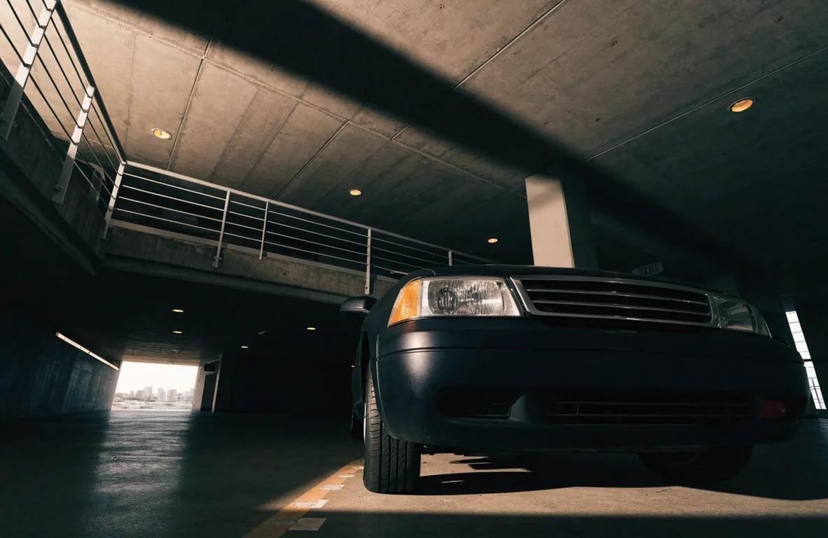 Car nose parked under a low concrete ceiling in a multi-level car park
