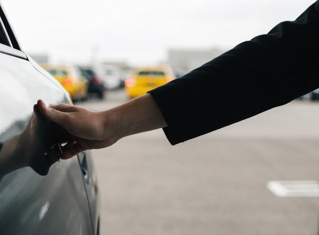 Hand closing a car door at a valet handover point on pavement
